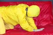 MARA ties, gagges and hoodes herself with cuffs and a ballgag on a sofa wearing sexy yellow rainwear (Pics)