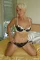 Short haired blonde MILF Claudia posing on bed