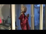 Blonde-haired archive girl being at home wearing shiny nylon rainwear (Video)
