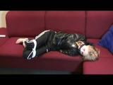 Samantha tied and gagged on a red sofa wearing a shiny black rainpants and a jacket (Video)