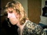 28 YEAR OLD HOUSEWIFE IS MOUTH STUFFED, WRAP TAPE GAGGED, TOE-TIED,  BLINDFOLDED, and HOG-TIED (D57-14)