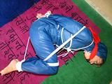 one of our archive girls tied and gagged in a shiny nylon rainsuit