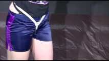 Mara wearing a sexy darkblue/purple shiny nylon shorts tied and gagged overhead with ropes and ballgag as well as a bar on the feet (Video)