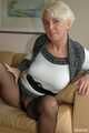 Pierced MILF Claudia posing in a knitted dress and pantyhose on the couch