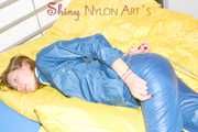 Alina wearing a sexy shiny rainwear suit in blue lolling on bed cuffed (Pics)