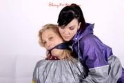 Sophie tied and gagged by Jill on a sofa wearing a shiny silver PVC sauna suit which is slitted by Jill (Pics)