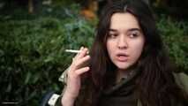 Young brunette is taking an unhurried stroll with allwhite 120mm cigarette