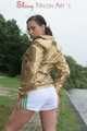 Watching out beautiful archive girl wearing a white shiny nylon shorts and a golden rain jacket posing outdoor (Pics)