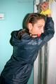 Stella tied and gagged in a shiny blue rainsuit