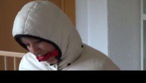 Mara tied and gagged on a chair wearing a supershiny blue down pants and a white monclear down jacket (Video)