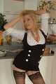 Pierced mature blonde Nina posing in a tight businessdress and stockings in front of the kitchen