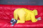 MARA ties, gagges and hoodes herself with cuffs and a ballgag on a sofa wearing sexy yellow rainwear (Pics)