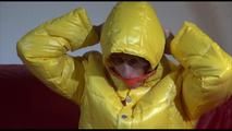 Sonja wearing a blue rain pants and a yellow PAMY down jacket while bonding herself an the sofa (Video)