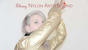 Mara wearing a sexy black shiny nylon shorts and a golden rain jacket tied and gagged with cuffs overhead (Pics)