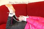 Mara tied and gagged on a red sofa wearing a sexy black rain pants and a shiny pink down jacket (Pics)