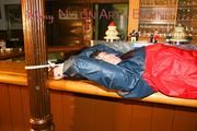 An archive girl tied and gagged on a bar wearing shiny nylon rainwear (Pics)