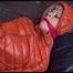 Pia tied and gagged on bed wearing a yellow rain pants and an orange downjacket (Video)