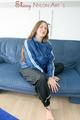 Katharina posing on a sofa wearing a blue/black shiny nylon rainwear (Pics)