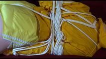 Lucy tied and gagged on a red sofa wearing a supersexy yellow shiny nylon shorts and a yelow rain jacket (Video)