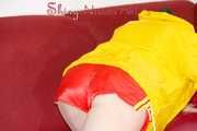 Lucy wearing a sexy red shiny nylon shorts and a yellow rain jacket preparing the sofa to lay down (Pics)