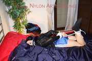 SEXY LUCY wearing a blue shiny nylon shorts and a black shiny rain jacket being tied and gagged with ropes and a clothgag on the bed (Pics)