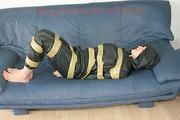 Katharina tied, gagged and hooded with tape on a sofa wearing sexy shiny nylon rainwear (Pics)