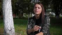 Pretty faced Asya is smoking a cigarette outdoors