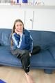Katharina posing on a sofa wearing a blue/black shiny nylon rainwear (Pics)