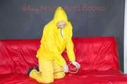 MARA ties, gagges and hoodes herself with cuffs and a ballgag on a sofa wearing sexy yellow rainwear (Pics)