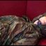 Jill tied, gagged and hooded on a red sofa wearing sexy shiny nylon camouflage rainwear (Video)
