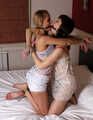 Gagged with a double ballgag, barefoot Dolly and Jessica, tied kneeling face to face, wiggles on the bed