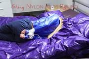Samantha tied and gagged on bed wearing a shiny darkblue nylon rain pants and a light blue rain jacket (Pics)