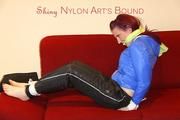 Mara tied and gagged on a sofa wearing a shiny black rain pants and a sexy lightblue down jacket (Video) 