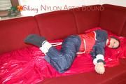 Lucy tied, gagged and hooded with ropes on a sofa wearing a sexy blue/red rainwear combination (Pics)