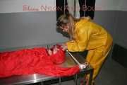 Watching Stella being tied and gagged with ropes and a ballgag on a operating table from Leonie both wearing sexy shiny nylon rainwear (Pics)