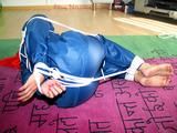one of our archive girls tied and gagged in a shiny nylon rainsuit