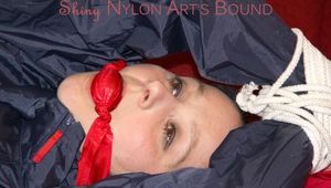 Lucy tied, gagged and hooded with ropes on a sofa wearing a sexy blue/red rainwear combination (Pics)