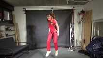 Marie in a custom video suspended in a shiny nylon Jumpsuit