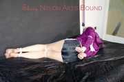 Pia tied and gagged on a bed with belts wearing a sexy black shiny nylon shorts and a purple shiny nylon rain jacket (Pics)