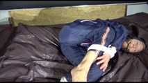 Sexy Sandra wearing a sexy blue shiny nylon pants and a sexy blue rain jacket tied and gagged with ropes and a cloth gag on a bed (Video)