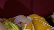 Lucy tied and gagged on a red sofa wearing a sexy yellow shiny nylon shorts and a yellow rain jacket (Video)