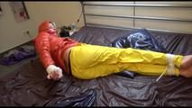 Pia tied and gagged on bed wearing a yellow rain pants and an orange downjacket (Video)