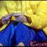 Sonja wearing a blue rain pants and a yellow PAMY down jacket while bonding herself an the sofa (Video)