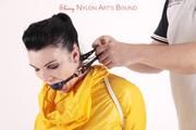 Jill tied and gagged in a shiny yellow rainsuit and rubber boots