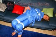 Katharina tied and gagged on a sofa wearing blue shiny downwear (Pics)