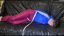 Mara tied, gagged and hooded on a sexy black covered sofa wearing a blue rain jacket and pink rain pants (Video)