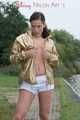 Watching out beautiful archive girl wearing a white shiny nylon shorts and a golden rain jacket posing outdoor (Pics)