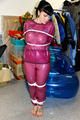 Jill tied and gagged in a semi-transparent purple PVC suit
