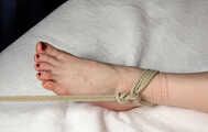 Tapegagged topless barefoot Bianca in jeans shorts, tied on the bed with her legs wide-spread, wiggles helplessly