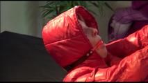 Pia tied, gagged and hooded on bed with a bar wearing y sexy black shiny nylon down pants and a red downjacket (Video)